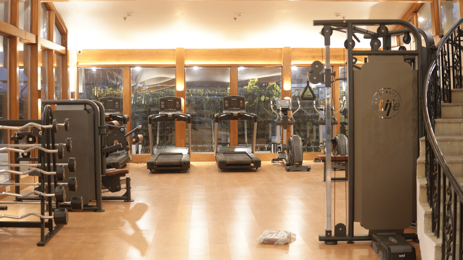 A fitness center with selectorized weight machines, cable stations, treadmills, and mirrored walls at Clarks Avadh, Lucknow.