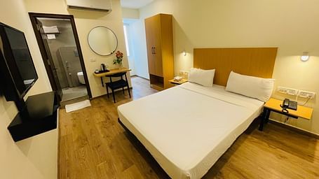 A double bed and a TV in a room along with a work desk at Sanctum Suites Richmond Road Bangalore