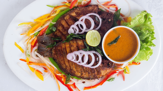 Kerala-style fried fish served with curry, fresh salad, and lime at the restaurant at Abad Brookside Lakkidi, Wayanad.
