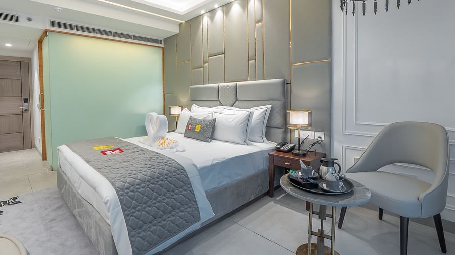 A well-decorated, contemporary bedroom with a large bed, stylish chair, and modern lighting fixtures at Mastiff Select Mandavya Dharamkot, McLeodgan