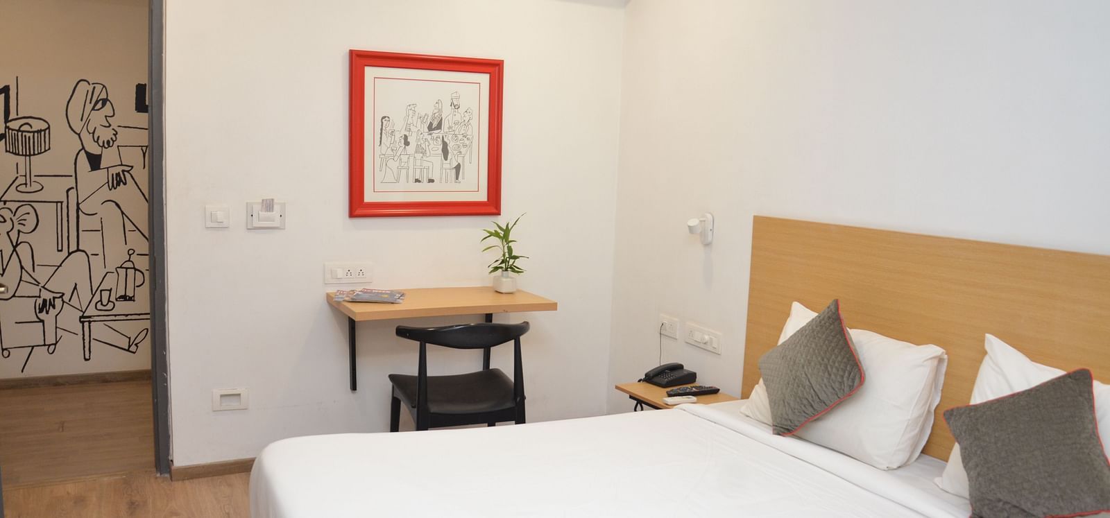 A bedroom with a double bed, bedside table, and a framed picture on the wall - Lords Eco Inn Belagavi