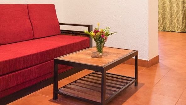 A small living area with a red sofa, a wooden coffee table, and a doorway leading to another room.