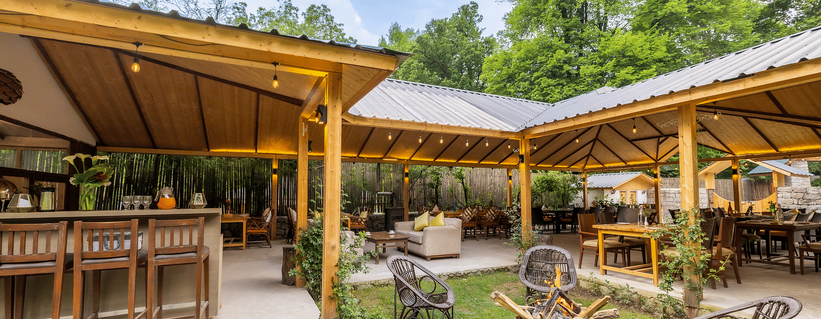 An open dining area with lavish wooden interiors, atttic style roof, wooden chairs and table at Bedzzz Xclusiv Baikunth, Manali