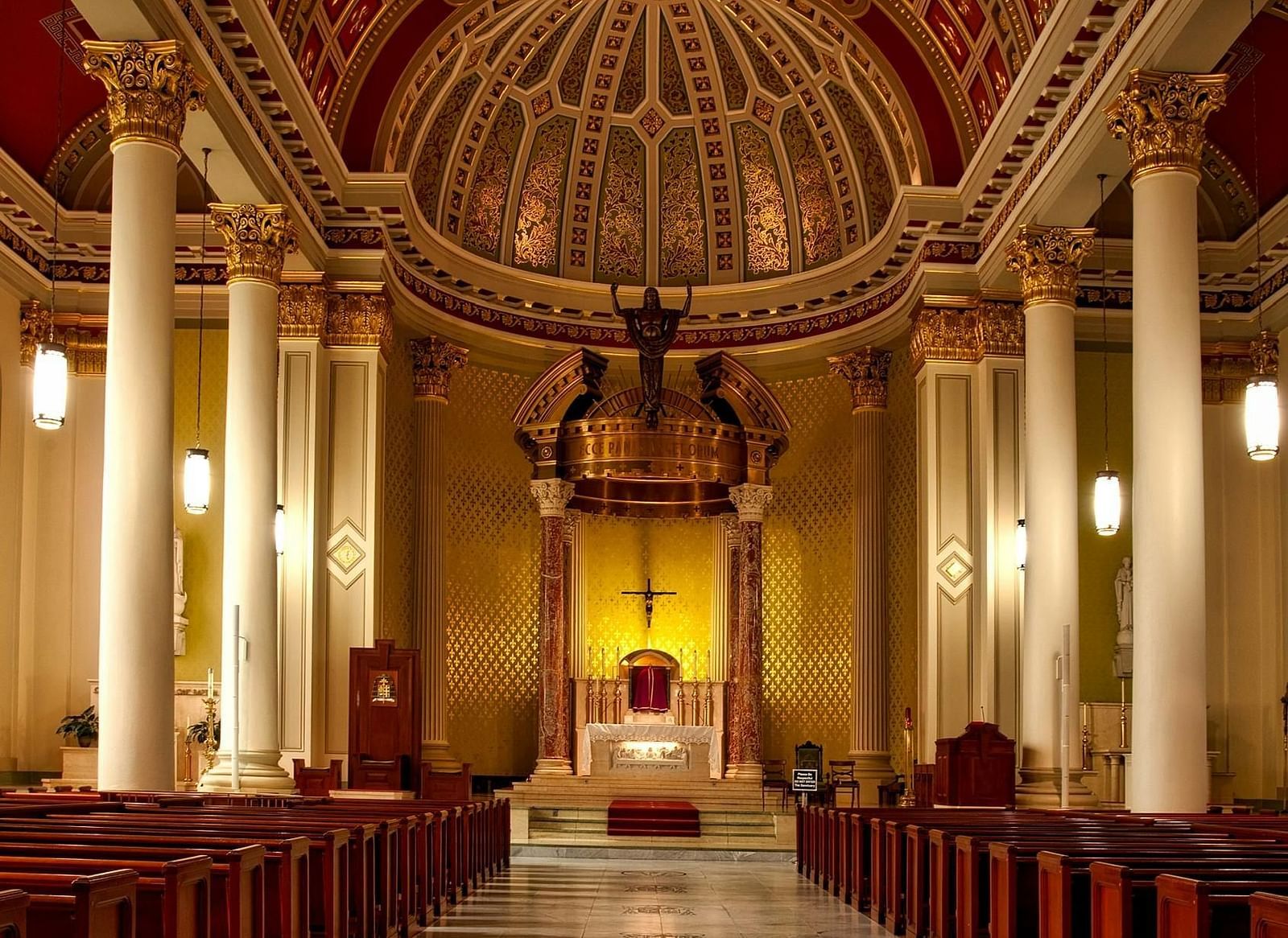 A grand view of a church’s interior, featuring an elegant vaulted ceiling and rows of wooden pews.