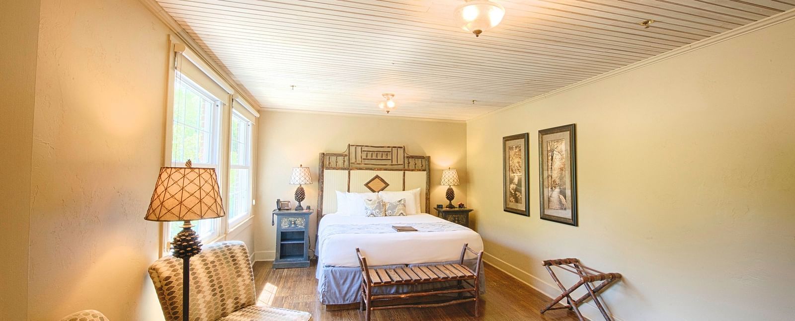 full view image of a bedroom with modern furnishings featuring a double bed along with two cushioned armchairs - Historic Tapoco Lodge