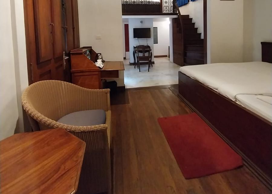 A picture featuring wooden flooring, a bed along with a coffee table and chair of superiror rooms - Le Dupleix - Pondicherry