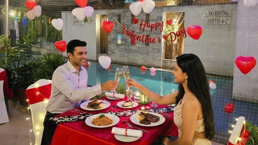 Couple enjoying a romantic poolside candlelight dinner with heart décor and balloons at Pride Plaza Ahmedabad on Valentine’s Day.