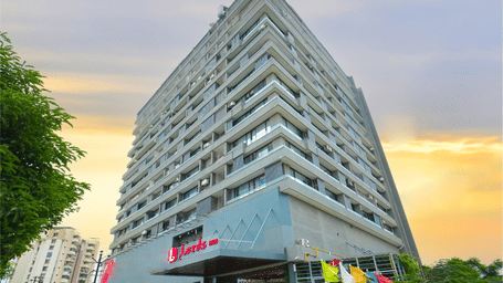 The exterior of the multi-story Lords Inn Rajkot building featuring the main entrance and hotel signage during sunset.