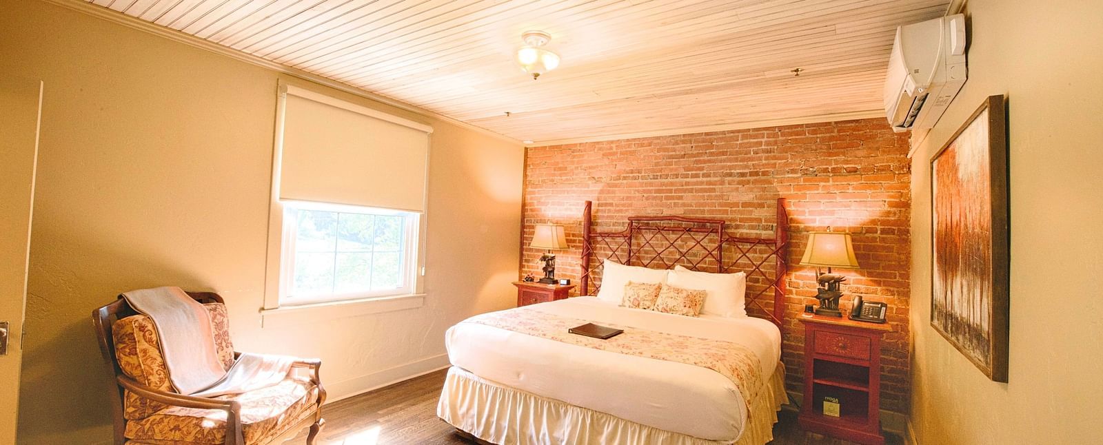 full view image of a bedroom featuring a bricked wall behind the double bed - Historic Tapoco Lodge