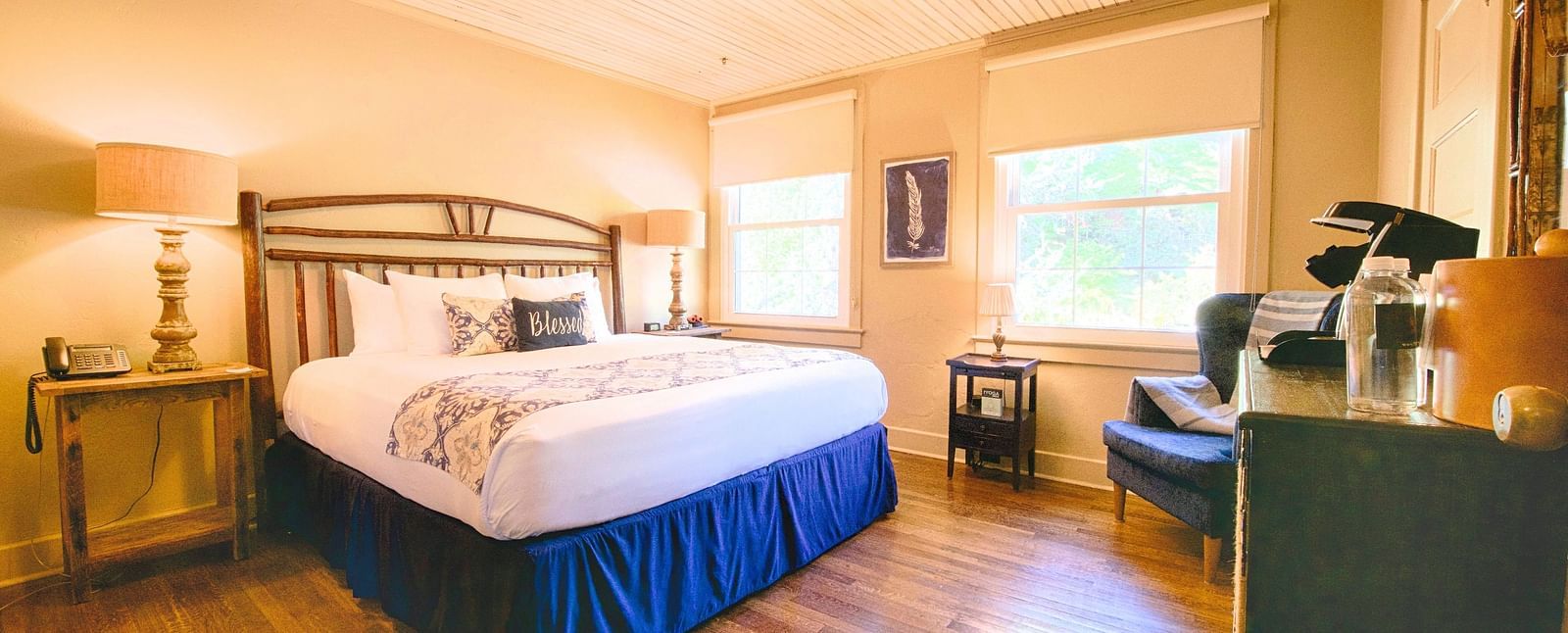 full view image of a room featuring a double bed with bed side tables along with a wooden cabinet in front of it - Historic Tapoco Lodge