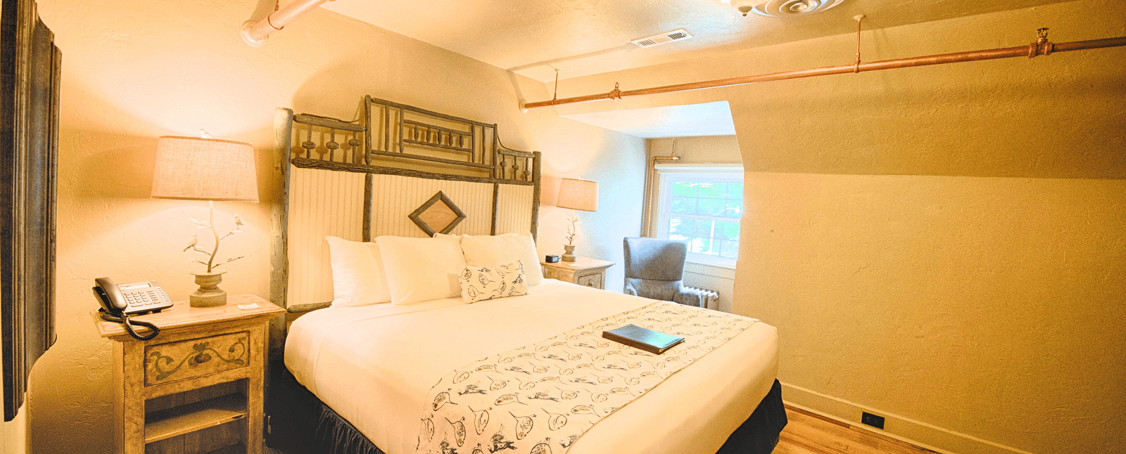a comfortable double bed with a huge head board behind it in a warmly illuminated room - Historic Tapoco Lodge