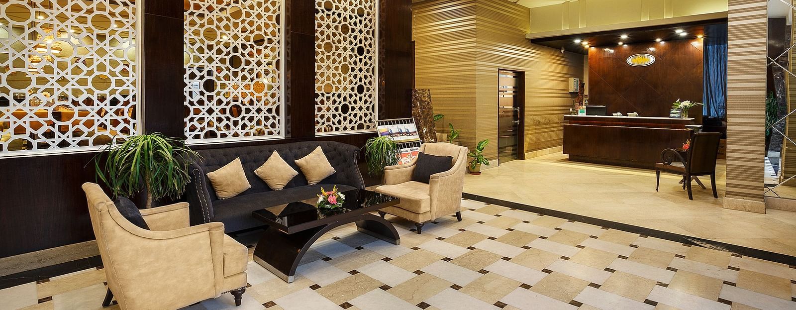 A sophisticated hotel lobby featuring a geometric patterned boards, plush seating, and a reception desk - The Manor, Bareilly