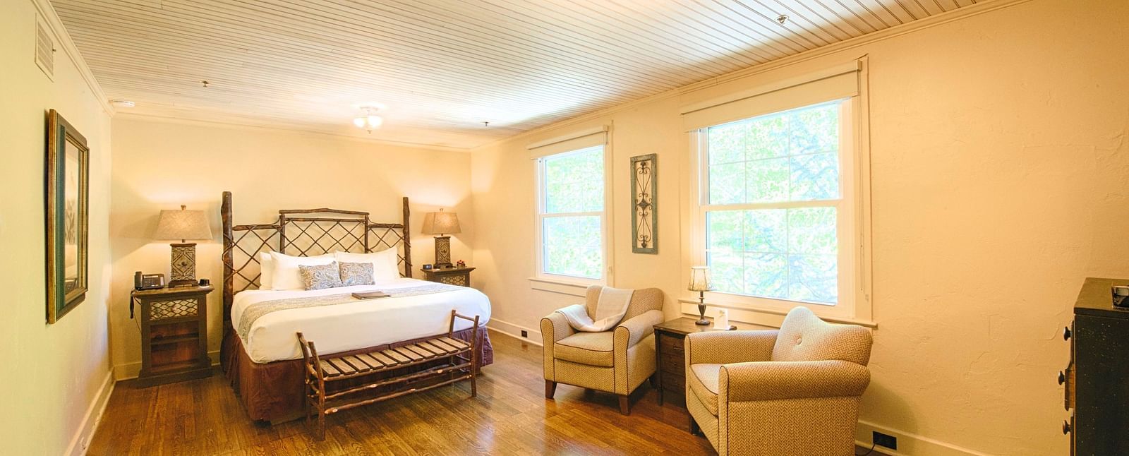 corner view image of a spacious bedroom featuring a common seating area along with a comfortable double bed - Historic Tapoco Lodge