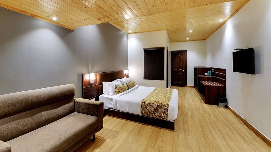 Side view of a double bed and a sofa in the Executive Deluxe Room at Hotel Sumitel Vista T.V Tower