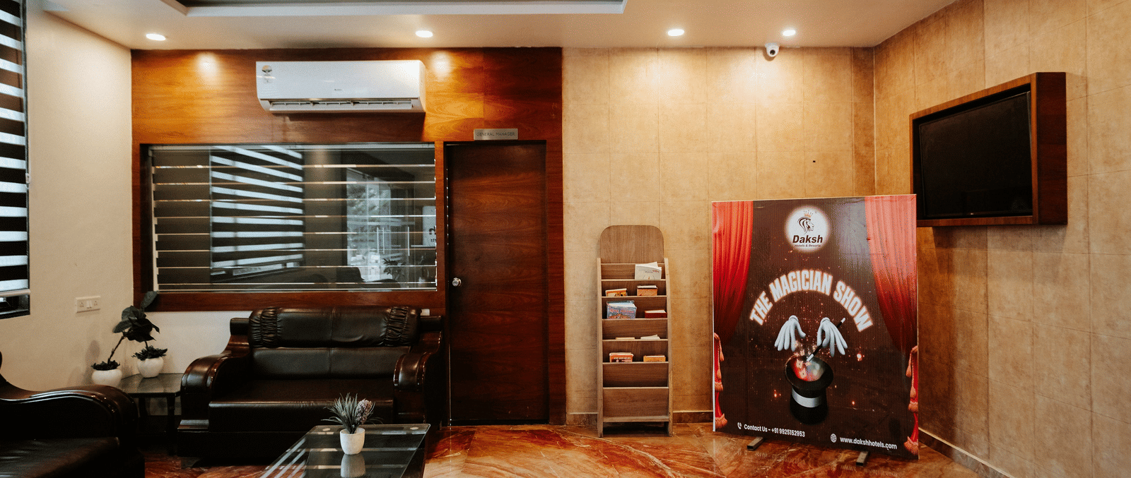 Interior view of a sleek hotel lobby or waiting area with warm lighting. Features marble flooring and modern furniture in black and brown tones at Daksh The Madhuvan Suites, Dwarka.
