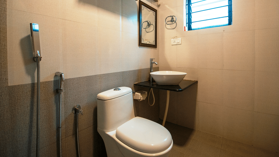 Image of a washroom with a toilet and a sink on the side at Coorg Jungle Camp Backwater Resort, Kushalnagar.
