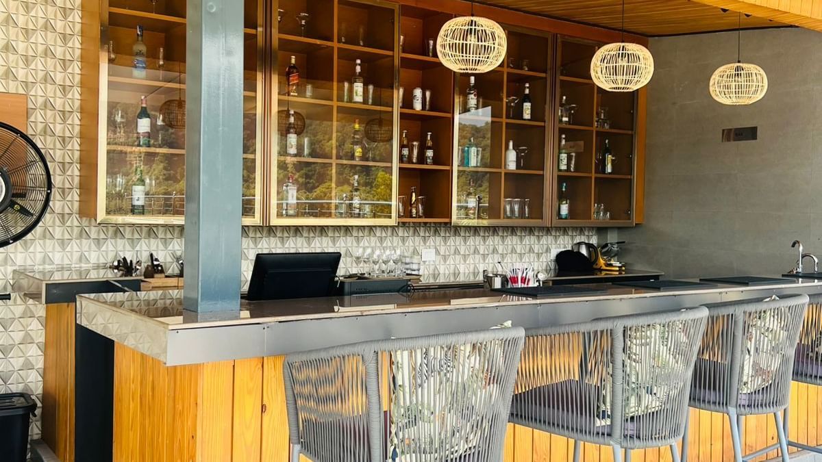 Clove bar at ABN Sarovar Portico, Jim Corbett with rows of metal high stool aligned in front of a yellow desk.