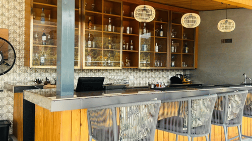 Clove bar at ABN Sarovar Portico, Jim Corbett with rows of metal high stool aligned in front of a yellow desk.