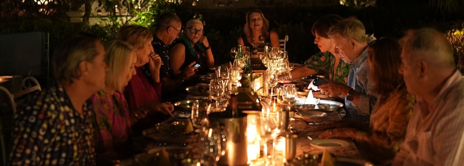 A group of people enjoying an evening meal together around a well lit table - Khas Bagh, Jaipur.