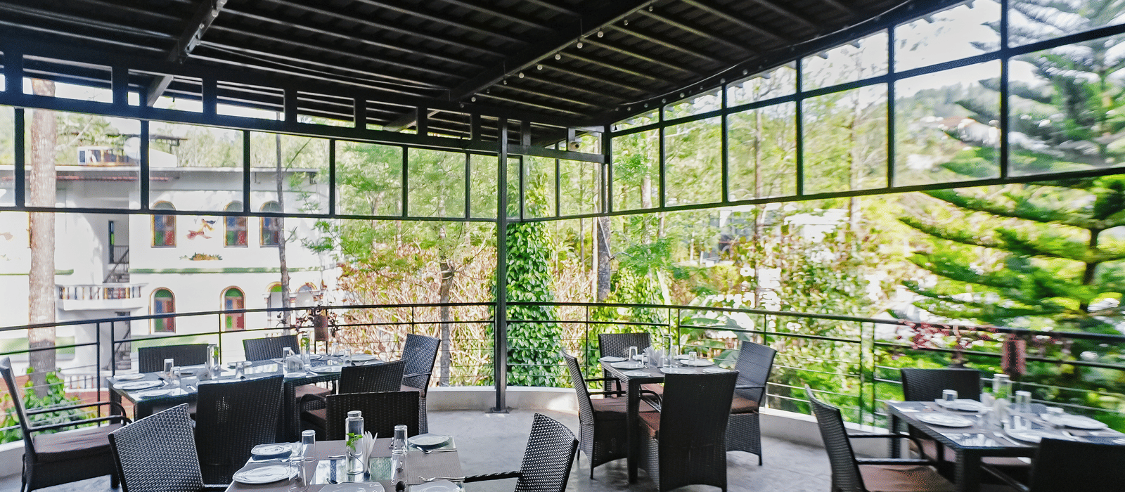 Covered outdoor dining area with tables and chairs neatly arranged at WOW Bungalow, Yercaud. 