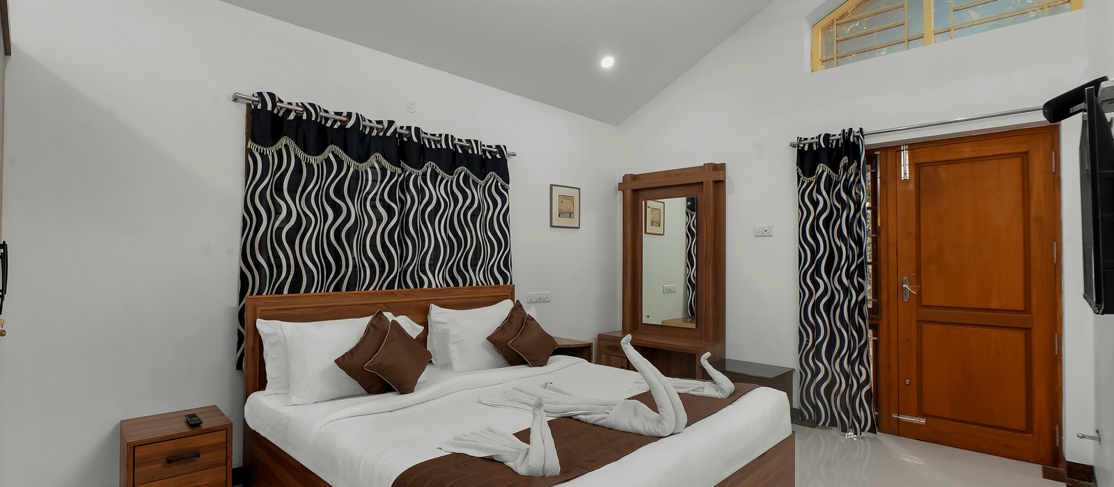 Diagonal view of a room showing a large bed with towel decorations at WOW Bungalow, Yercaud. 