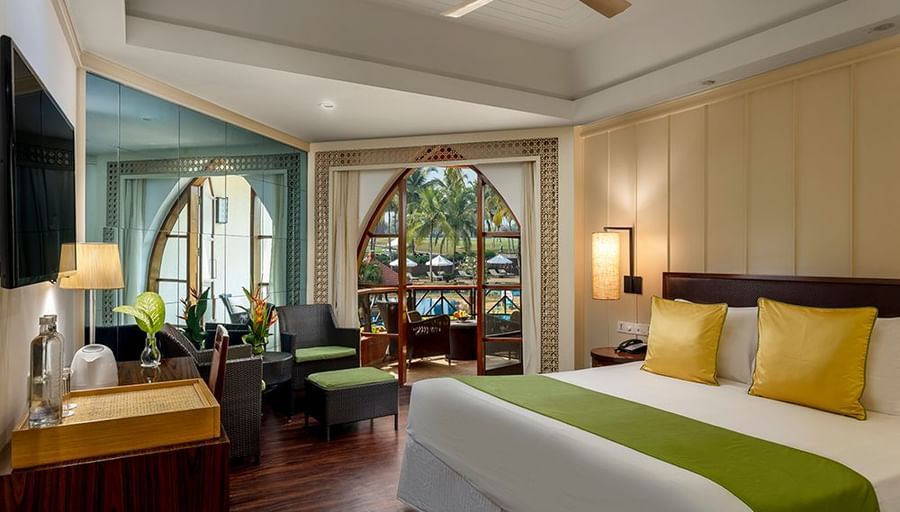 a double bed, tv, chairs and lamps inside Deluxe Room - Caravela Beach Resort Goa