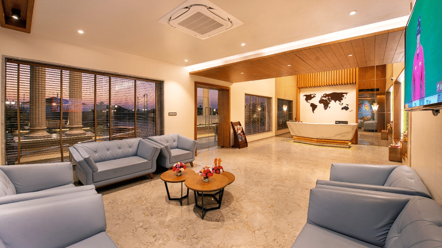 A well-lit lobby at Lords Inn Jamnagar with partial wooden panelling, sofas, and a large window offering an outdoor view.