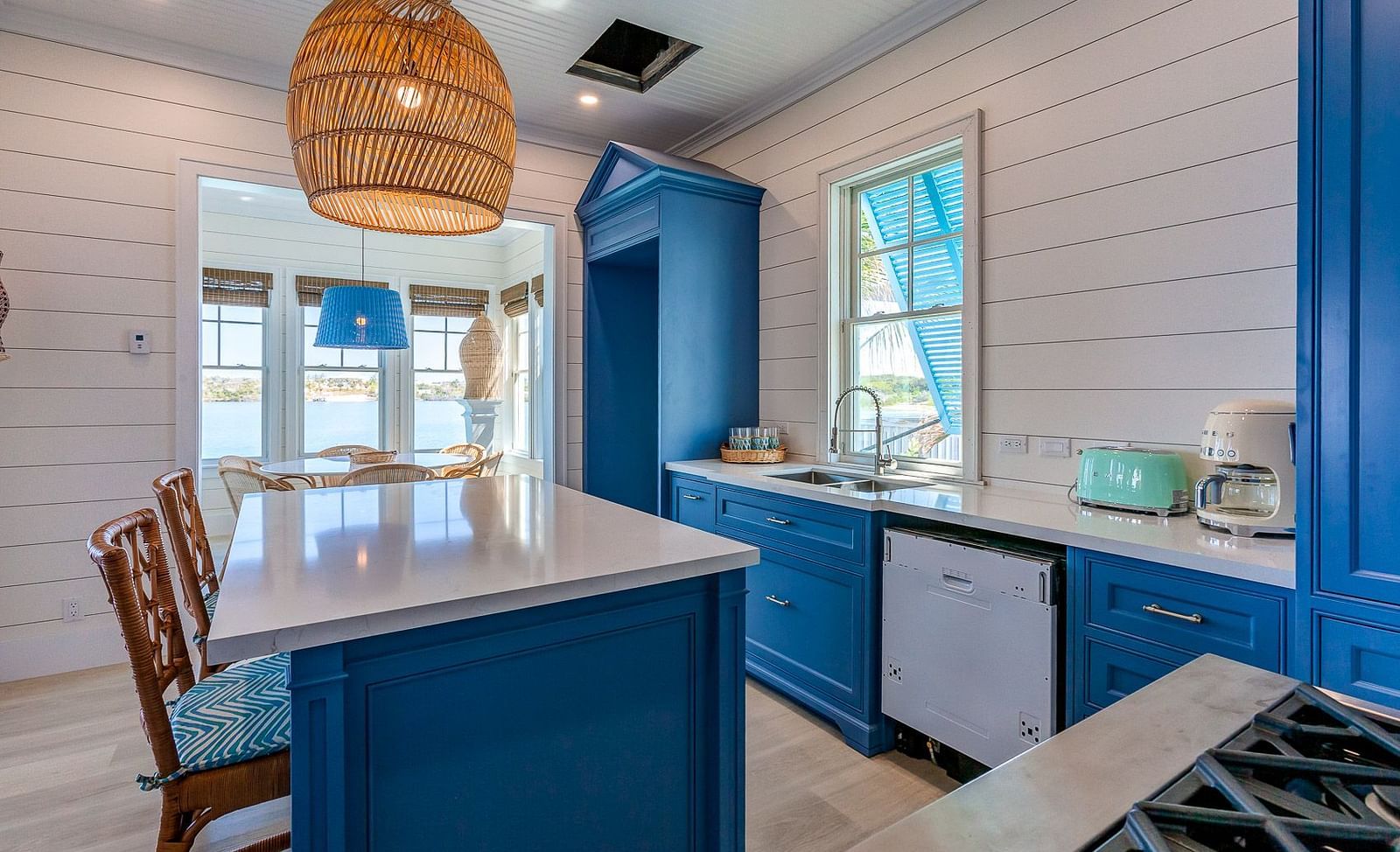 Kitchen with a navy blue island, barstools, pendant lighting, and white shiplap walls | Abaco Inn