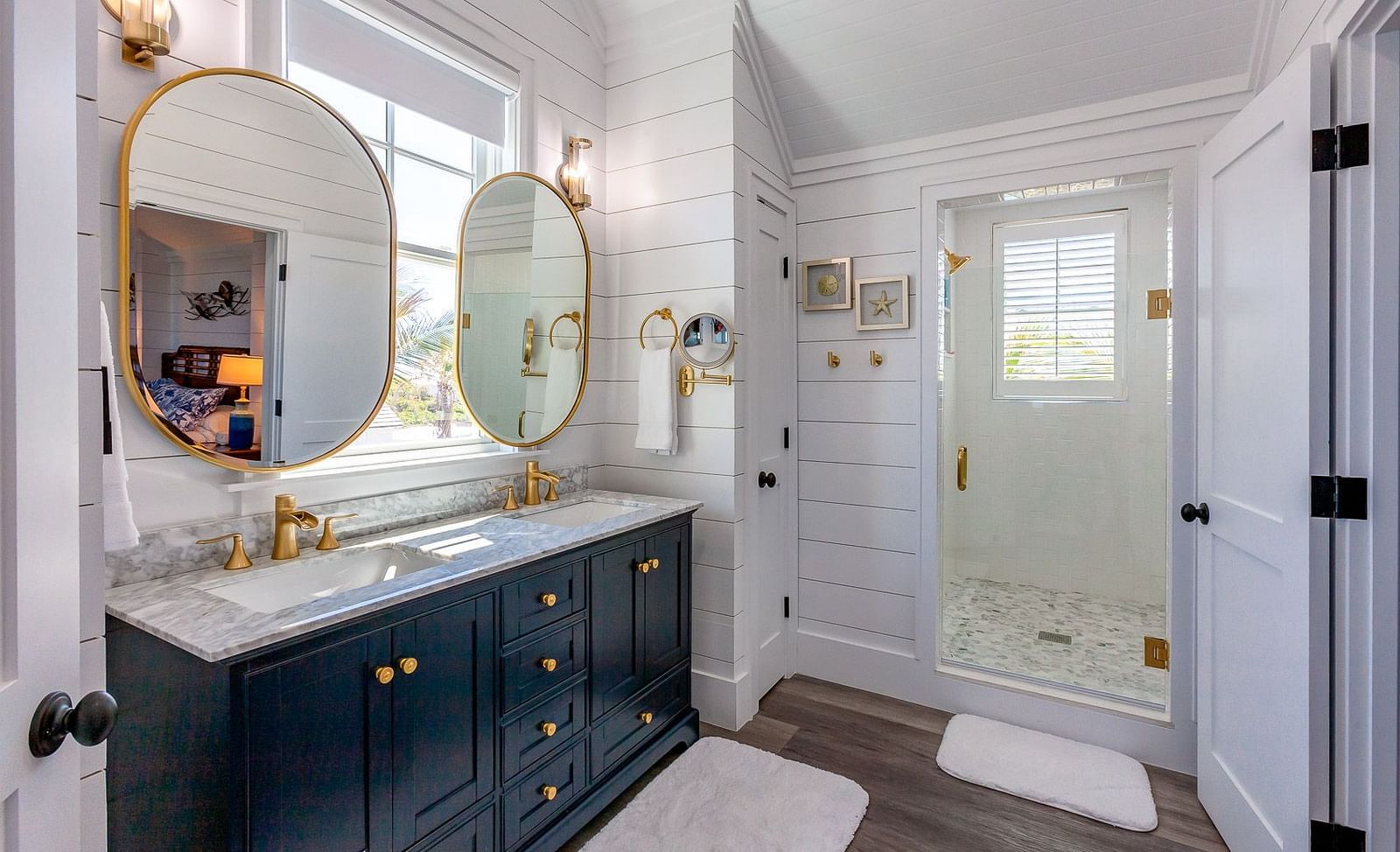 Bathroom with dual sinks, gold-framed mirrors, and a glass door | Abaco Inn