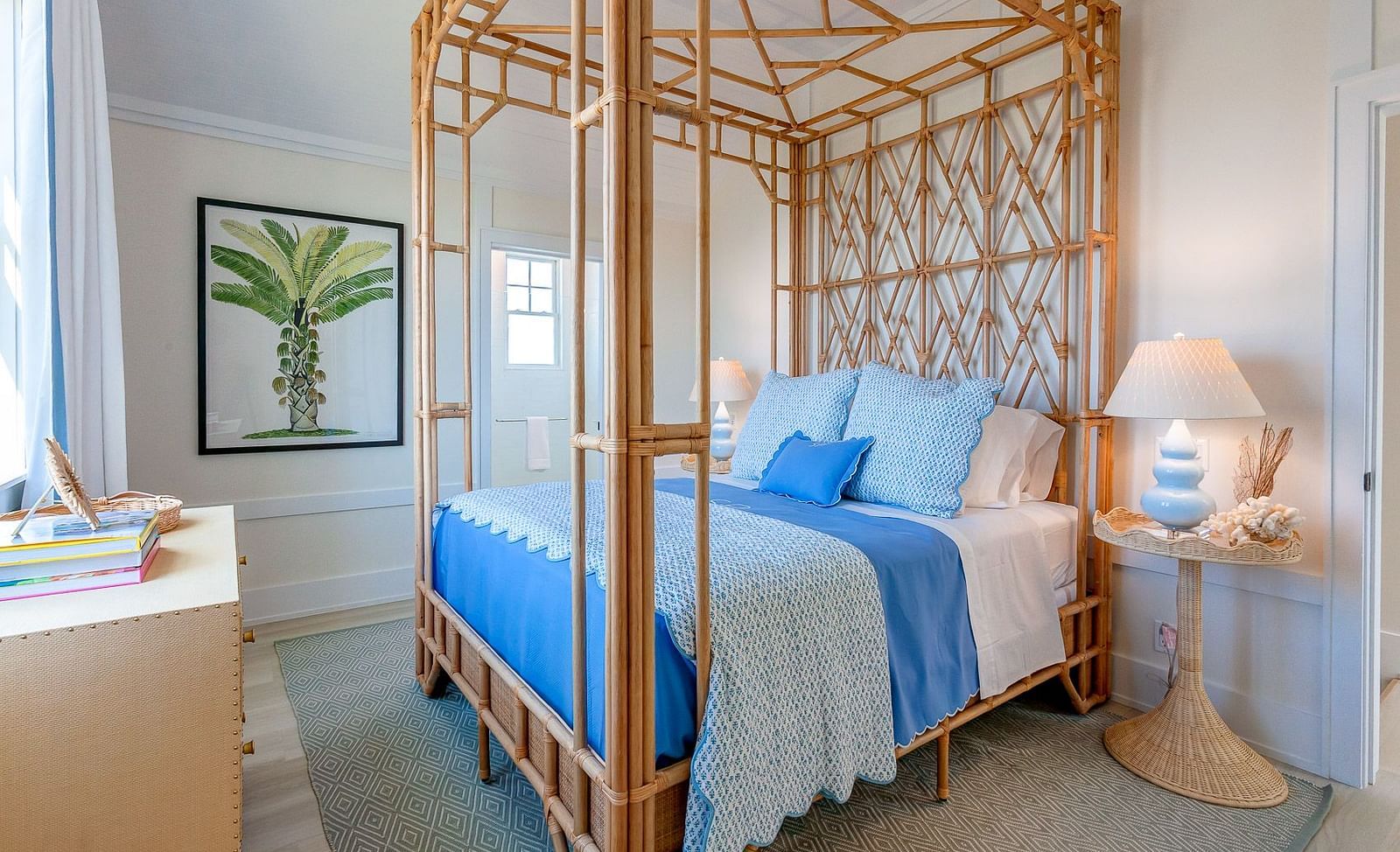 Bedroom with a rattan four-poster bed, blue bedding, and a framed botanical artwork on the wall | Abaco Inn