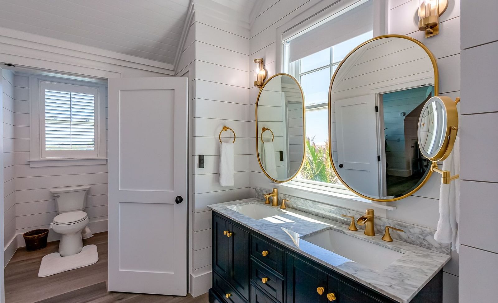 Bathroom with dual sinks, gold-framed mirrors, and a glass shower door | Abaco Inn
