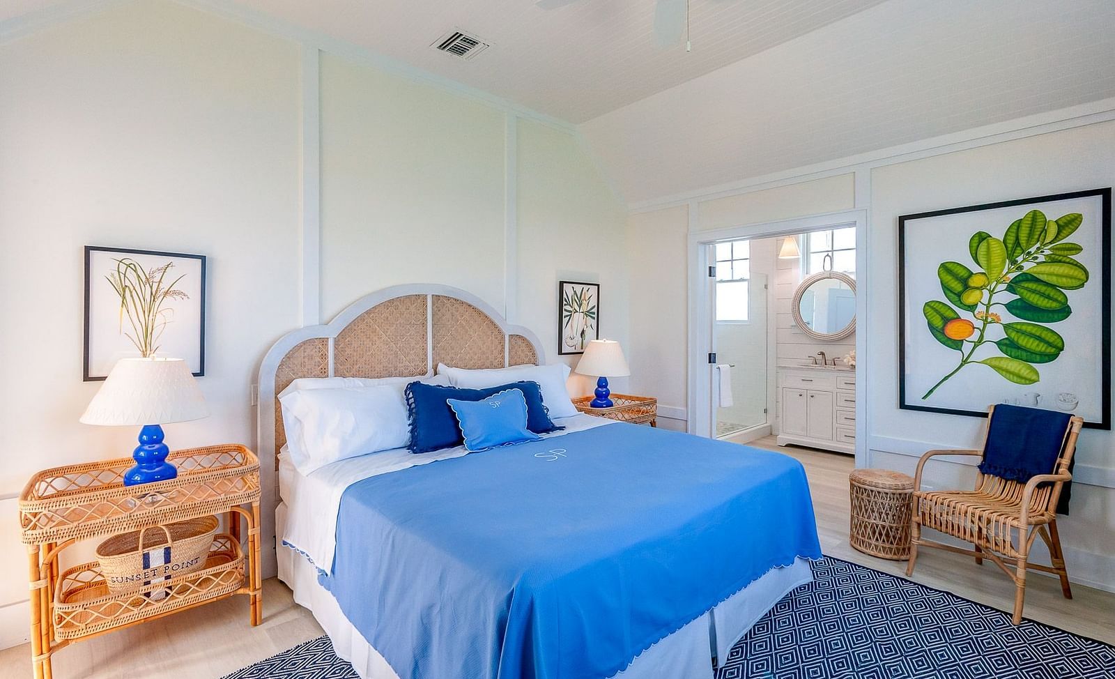Bright bedroom with a woven headboard, blue bedding, wooden furniture, and framed botanical wall art | Abaco Inn