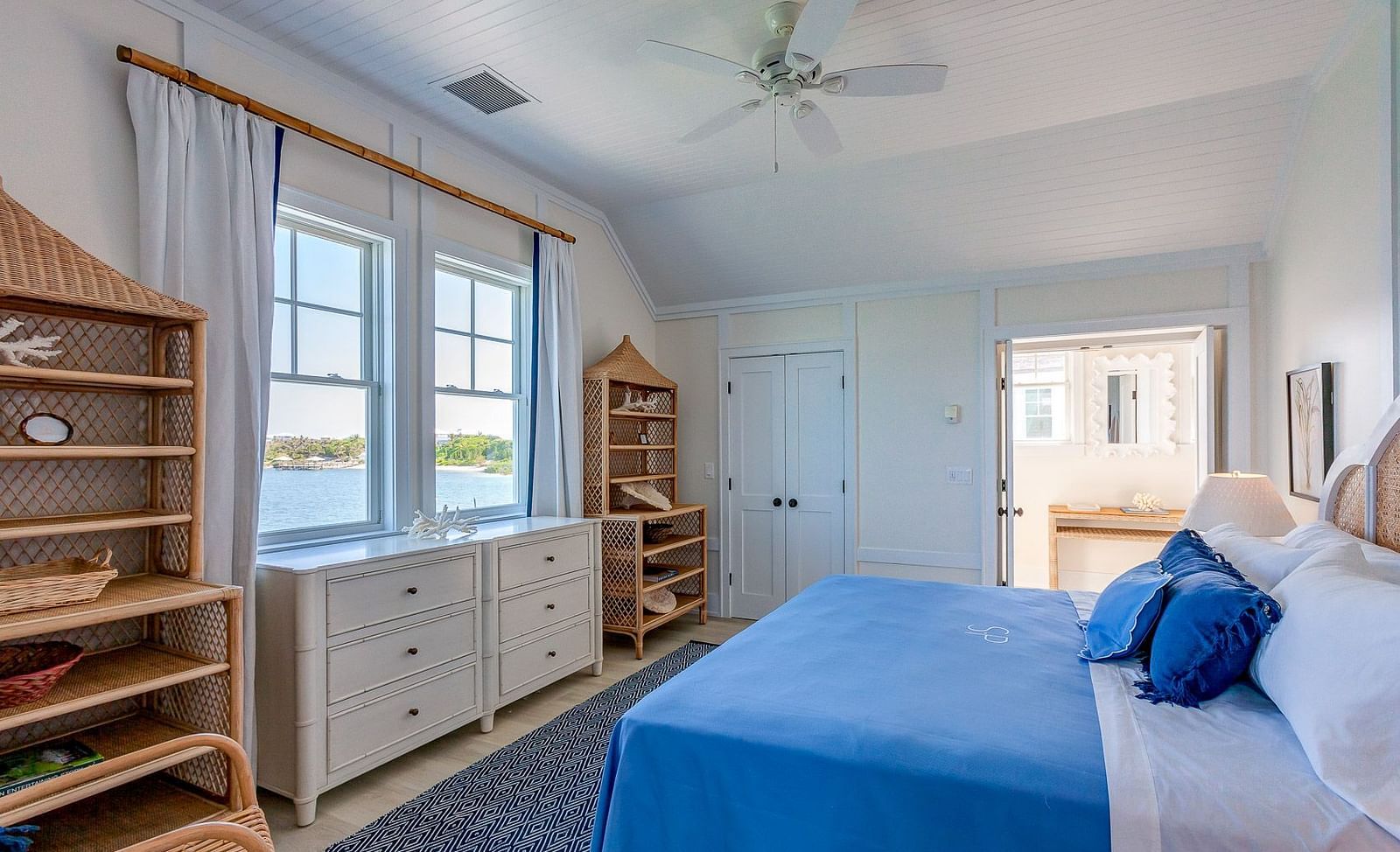 Bright bedroom with a blue bedspread, wooden shelving, and large windows allowing natural light | Abaco Inn