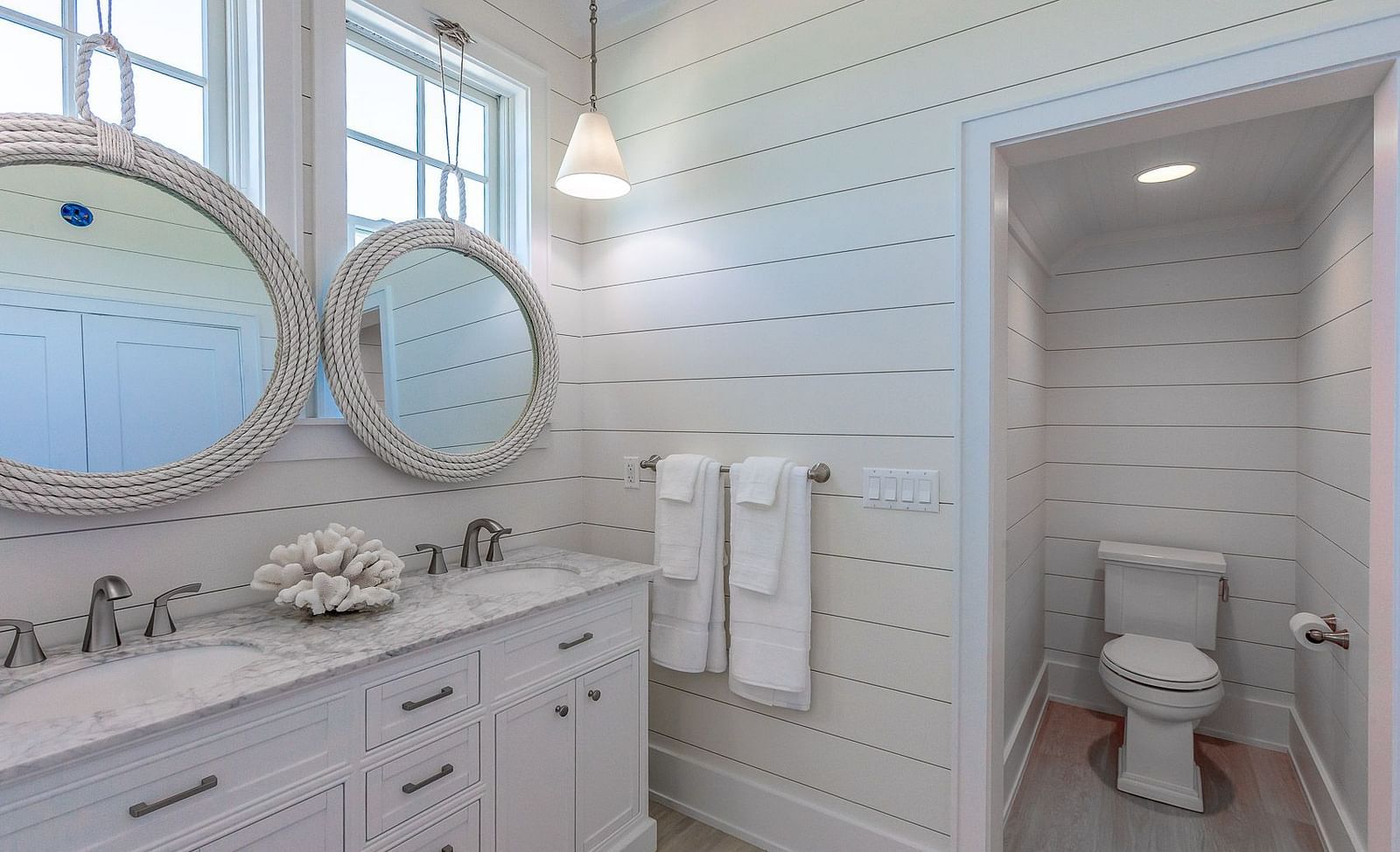 Bathroom with a white double vanity, two round mirrors, and a separate toilet area | Abaco Inn