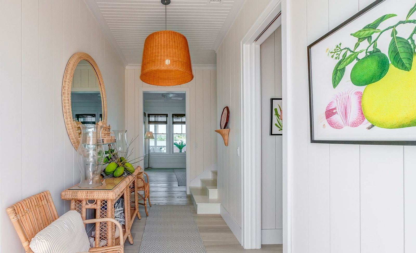 Hallway with wicker furniture, a round mirror, and an orange pendant light | Abaco Inn
