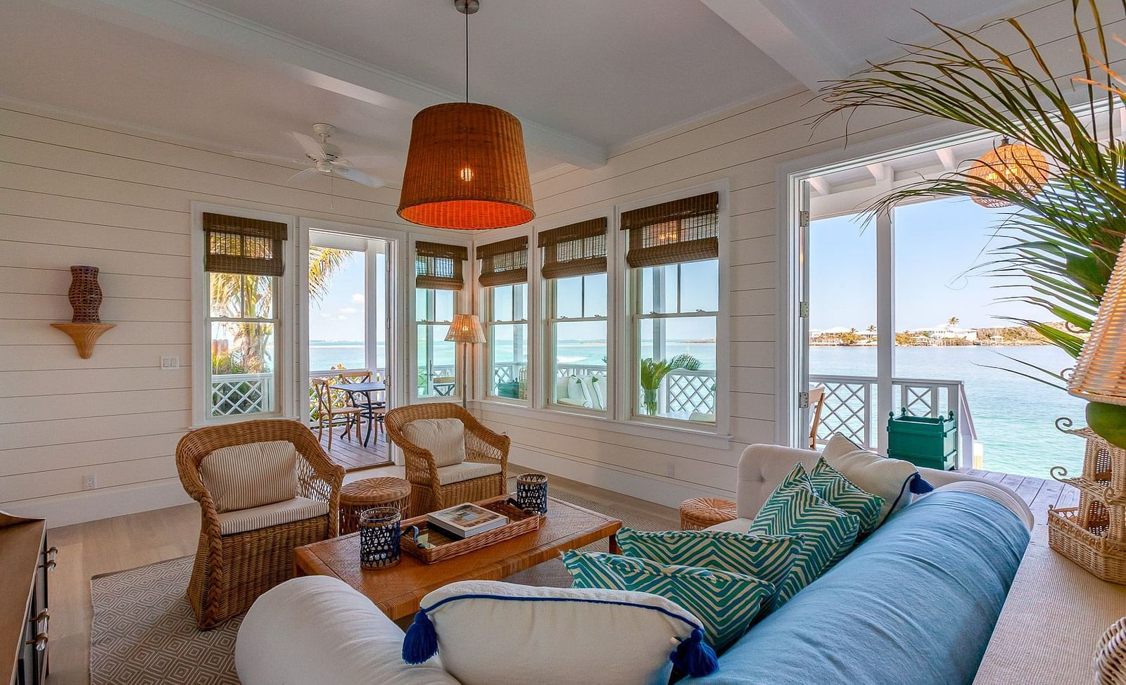 Living room with sofas, wicker chairs, and a view of the ocean through large windows | Abaco Inn