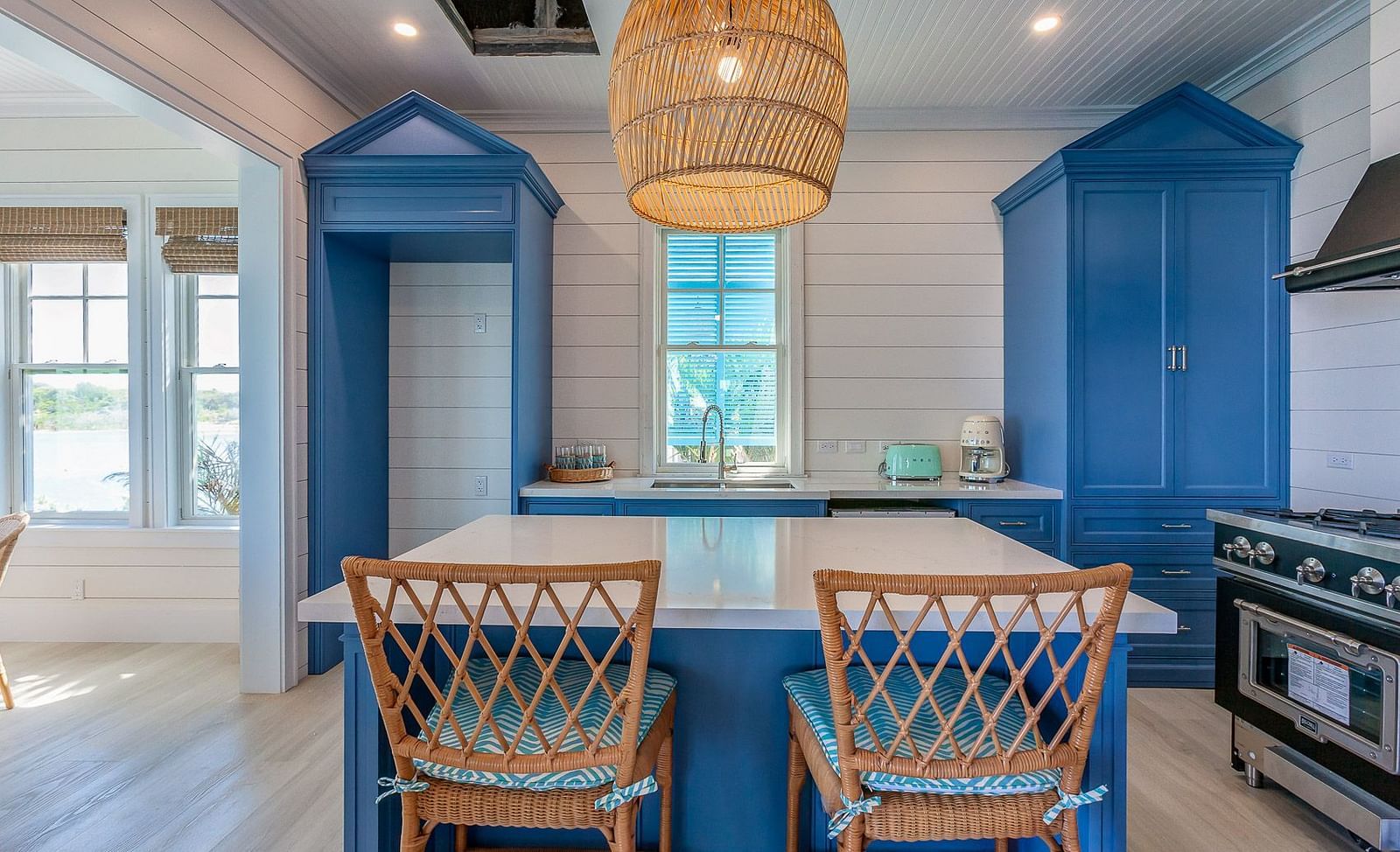 Kitchen with blue cabinets, rattan pendant lights, and a breakfast bar with wicker stools | Abaco Inn