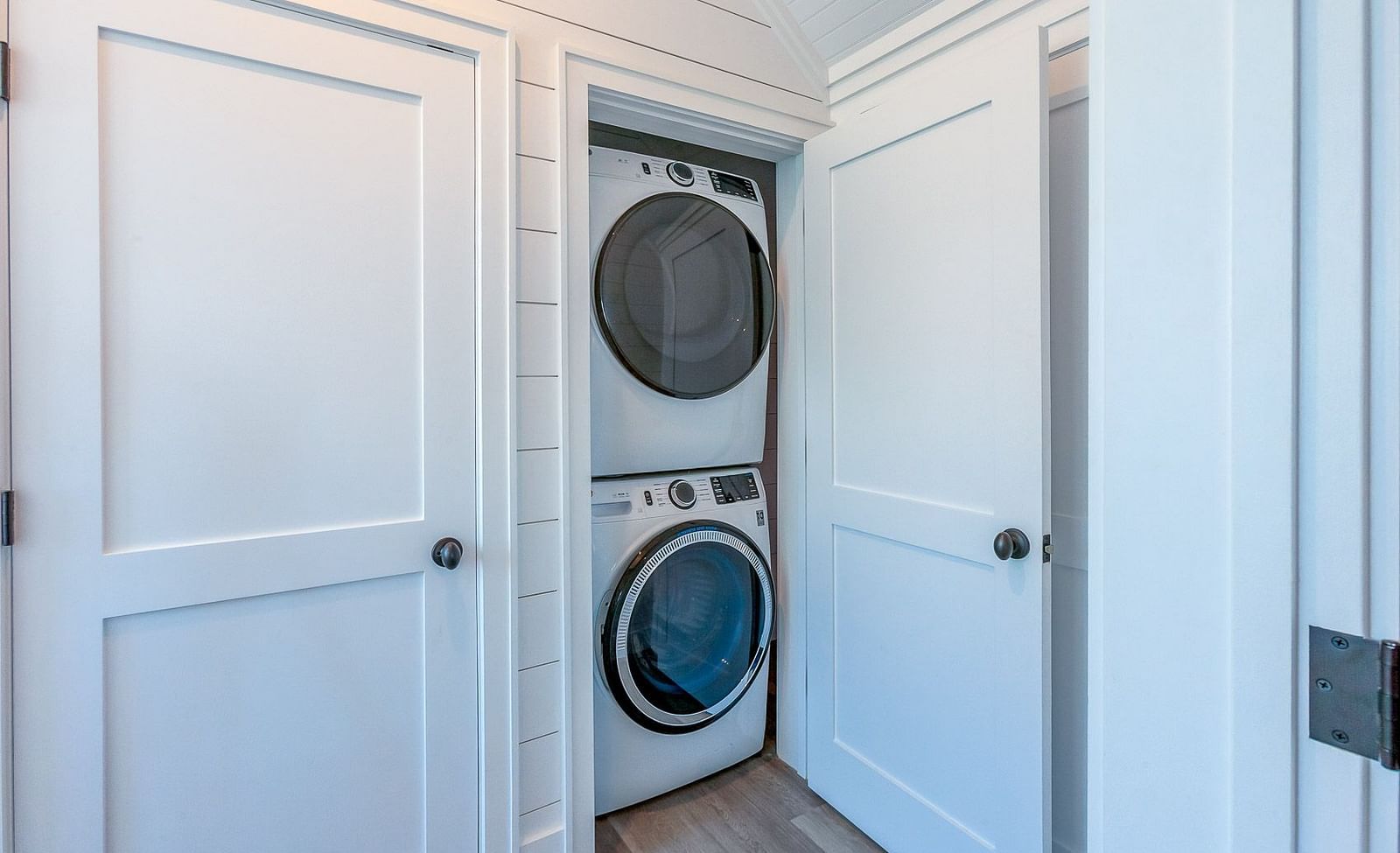 Laundry area with stacked washer and dryer behind white doors | Abaco Inn