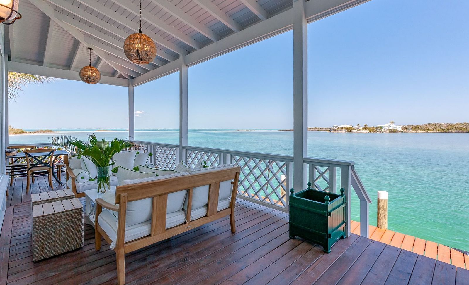 Spacious balcony with cushioned seating, wooden flooring, and panoramic ocean views under a clear blue sky | Abaco Inn