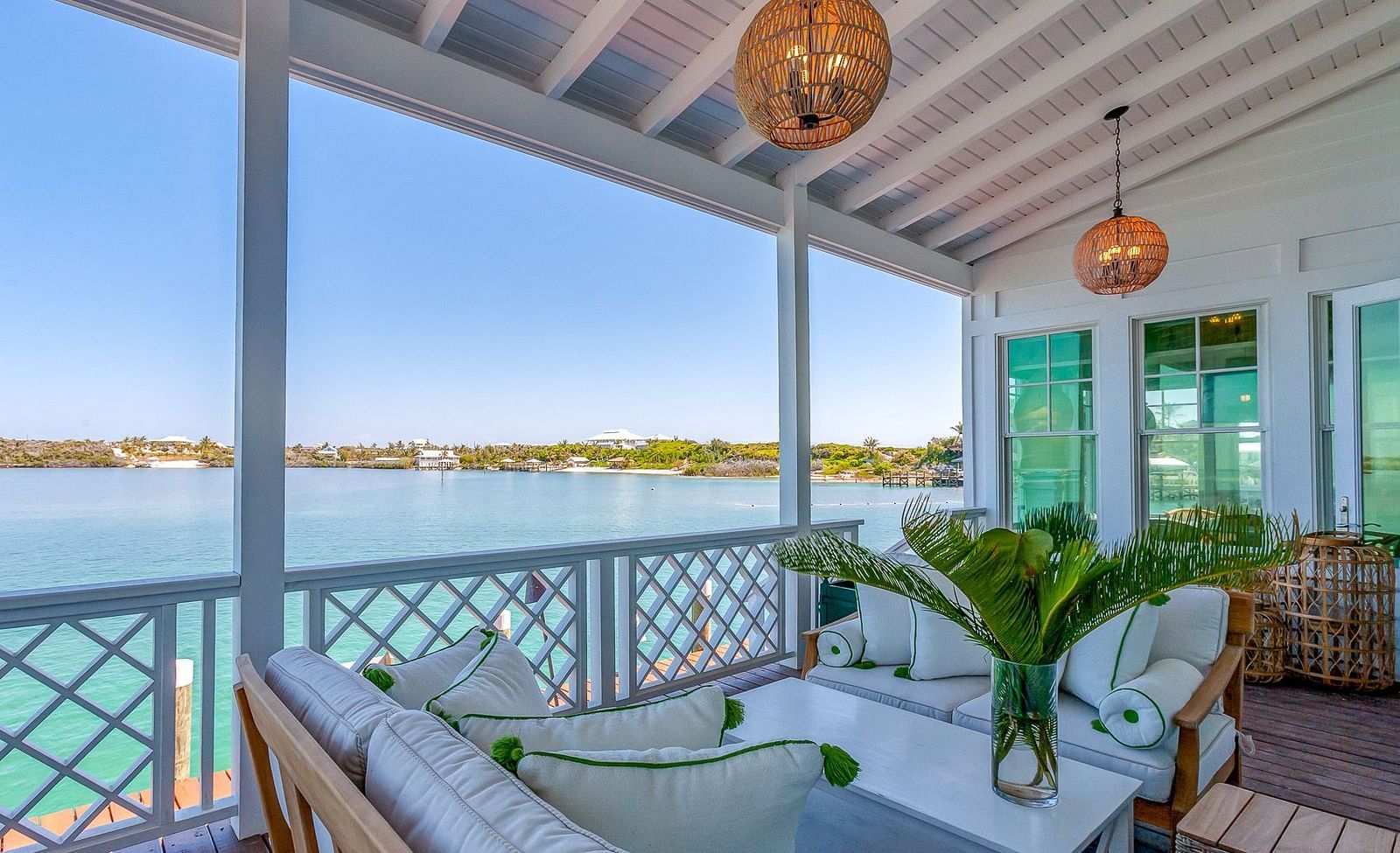 Covered porch with cushioned lounge seating, pendant lighting, and a scenic ocean view in the background | Abaco Inn