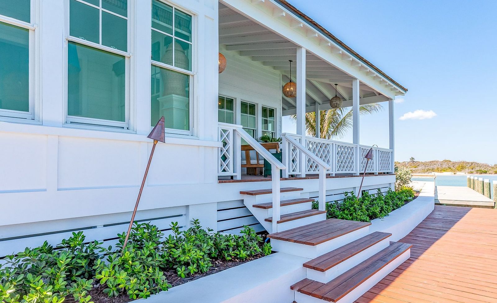 White coastal-style house with green shutters, a porch, and landscaped steps leading to the entrance | Abaco Inn