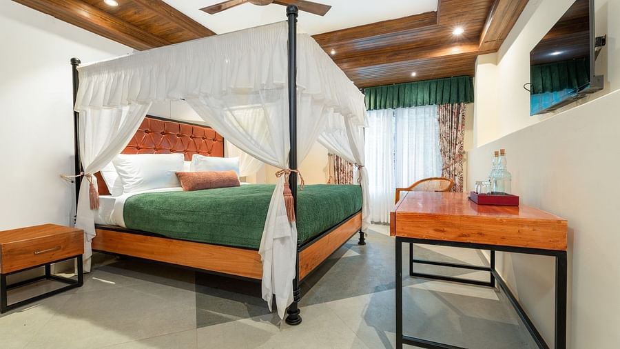 A generously sized bed with well-lit illumination, accompanied by wooden furniture