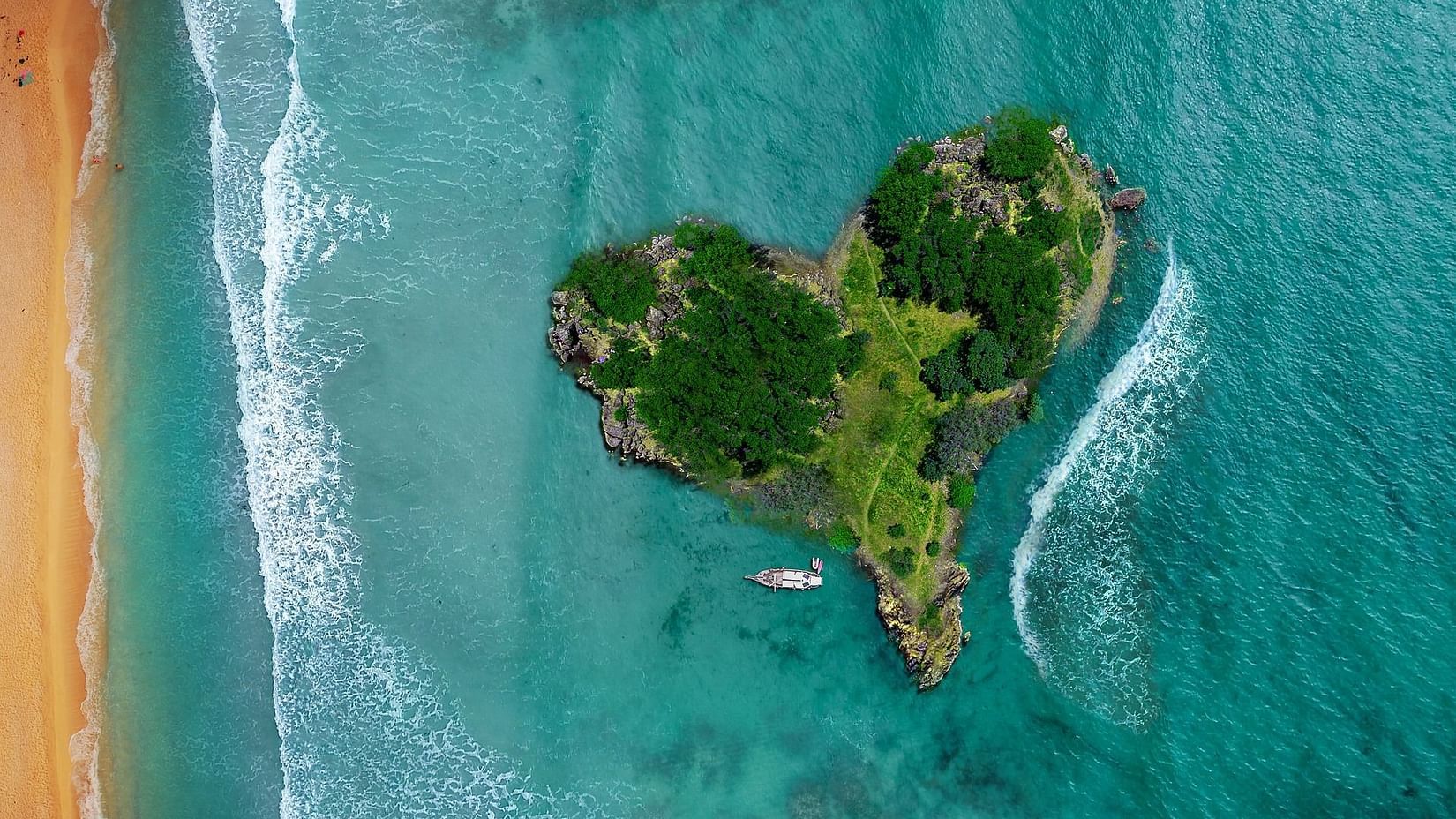 an aerial view of a heart-shaped island near a beach with water overlapping on it