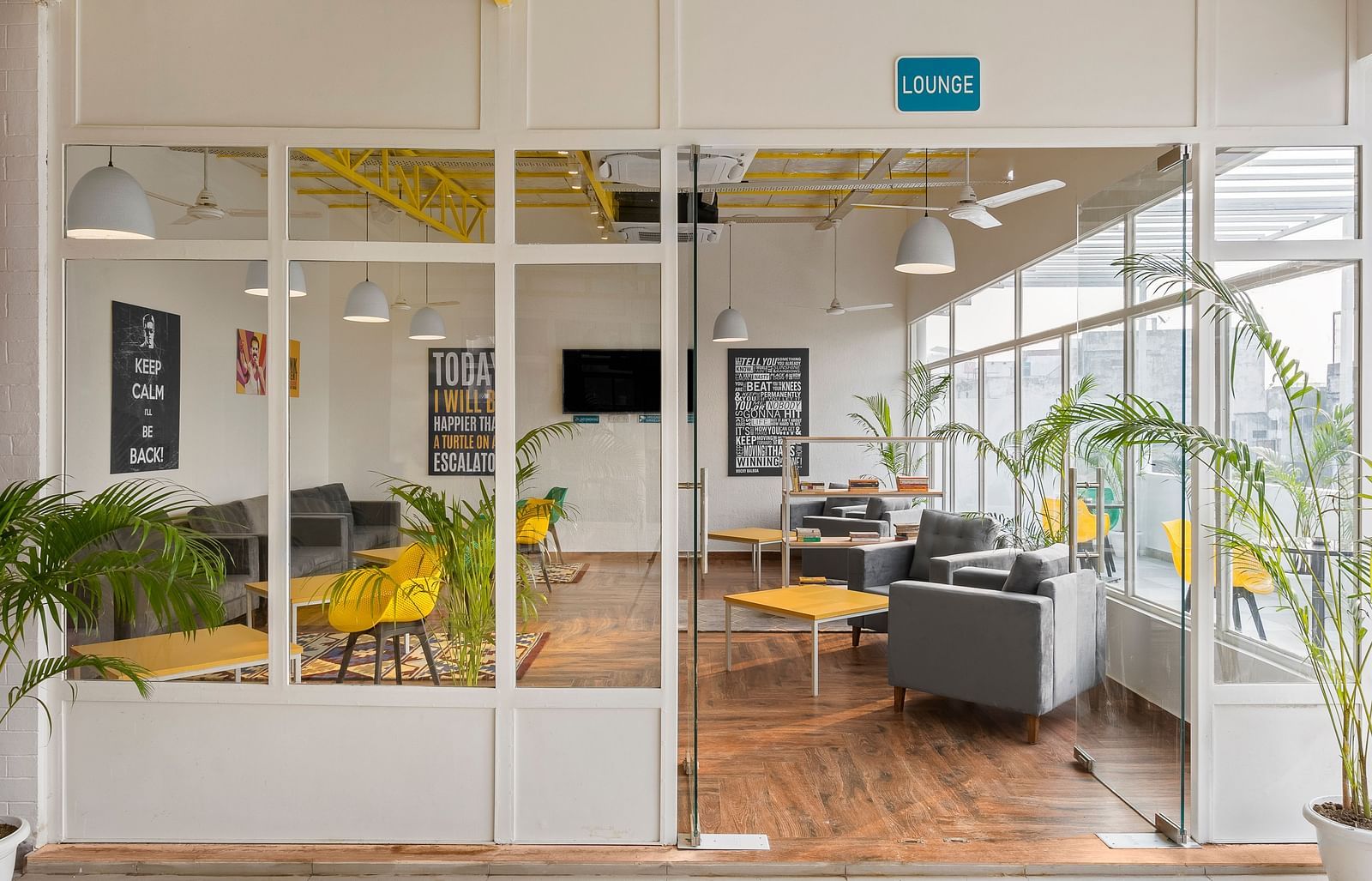 An image of a lounge area from outside, featuring sofas and bean bags for relaxation, coffee tables, and a bookshelf stocked with a selection of books to read.