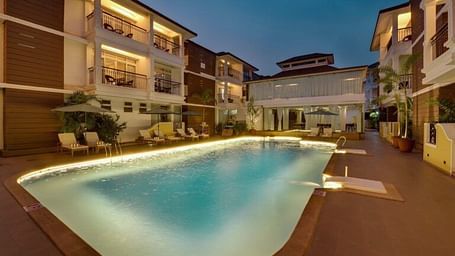 The exterior view of verda resort with swimming pool surrounded by tall buildings. 
