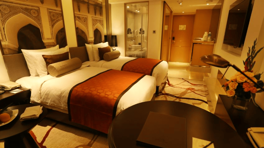 Deluxe Twin Room at Pride Plaza Hotel, New Delhi featuring twin beds, bedside tables with lamps, centre table, tea and coffee maker, and an attached bathroom.