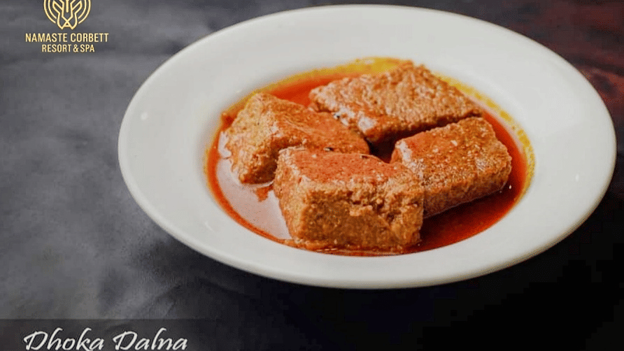 Dhokar Dalna, Bengali lentil dumplings cooked in rich red gravy, served in a white bowl.