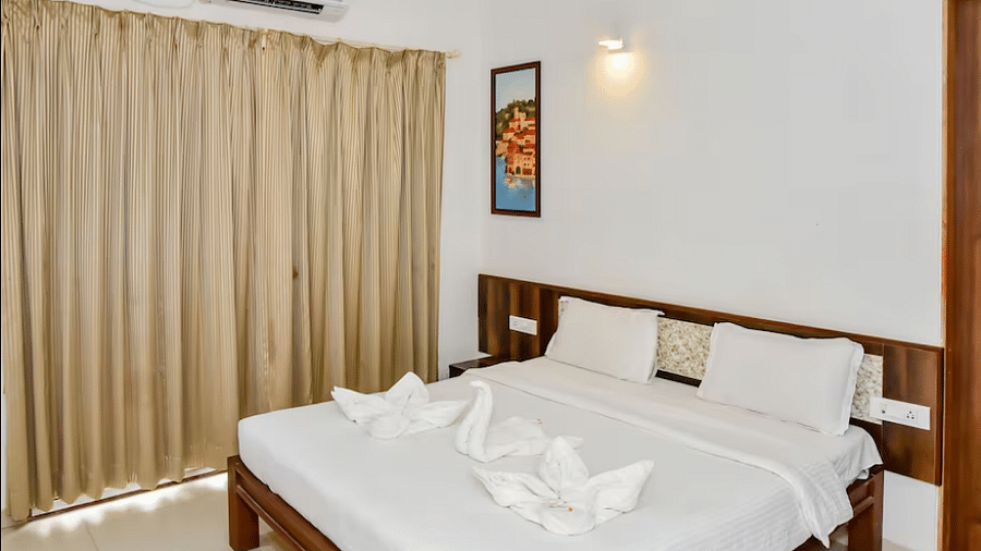 Well-lit bedroom with a spacious bed, curtained windows, and towel swan decorations at La Vida Studio Inn.