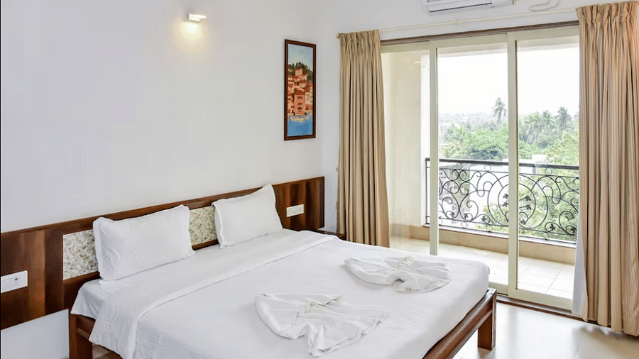 Bright bedroom with white linens, balcony doors, and wall-mounted artwork at La Vida Studio Inn.