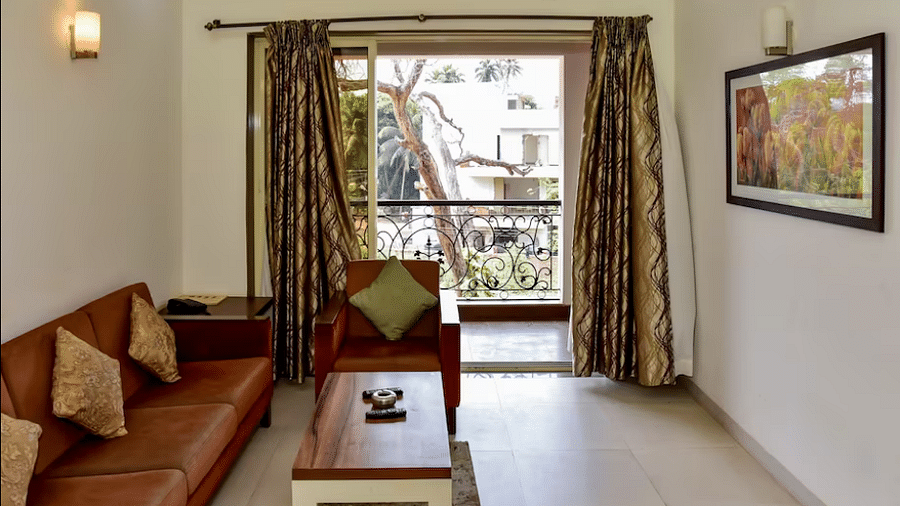 Living area with a sofa, table, and balcony view at La Vida Studio Inn Goa.